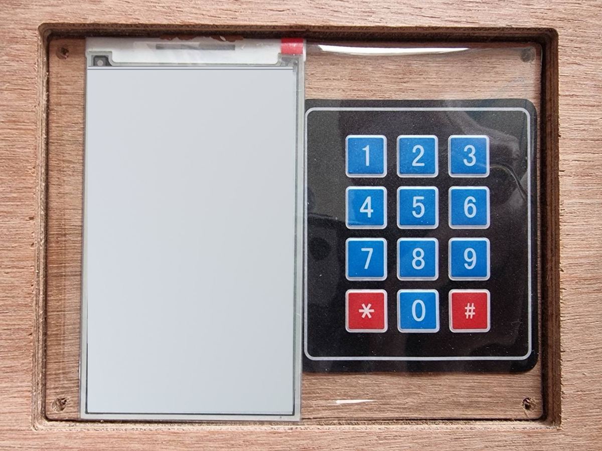 E-ink displej a klávesnice 4 × 3 zabudované v přední desce automatu; obsah displeje je na fotografii vymazaný